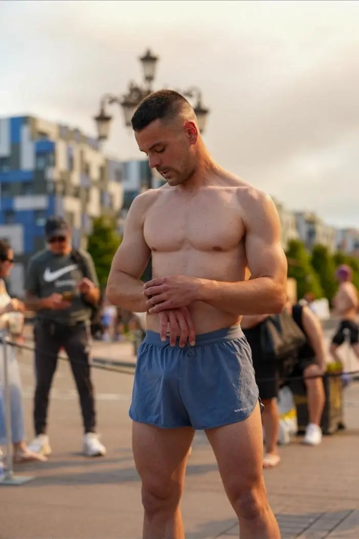 Antonio Jamart consultando su reloj deportivo antes de una prueba, con la musculatura del torso y los brazos a la vista