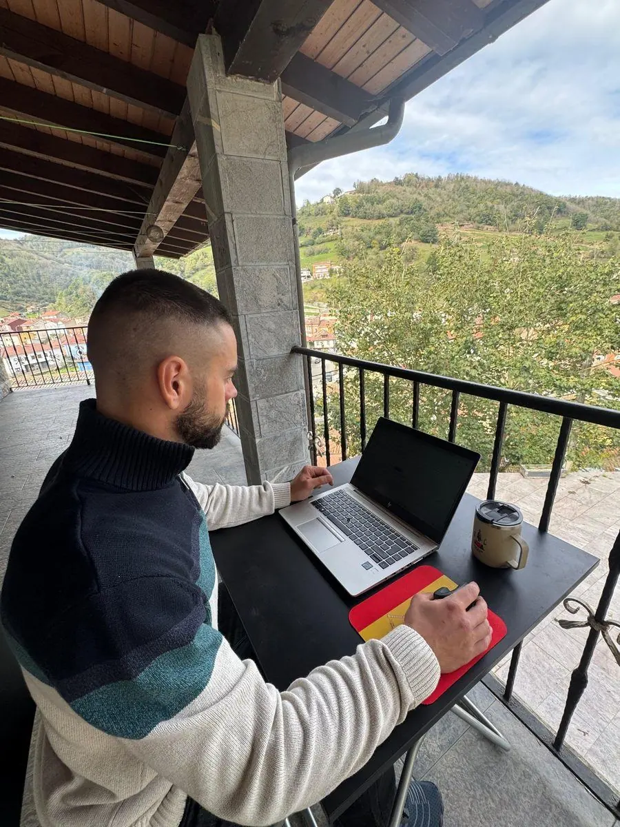 Antonio Jamart preparando planes de entrenamiento con su portátil en una terraza con vistas al valle